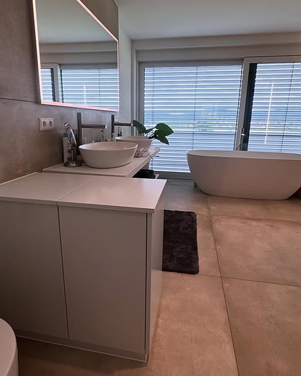 Modernes Bad mit weißem Waschtischmöbel und freistehender Wanne